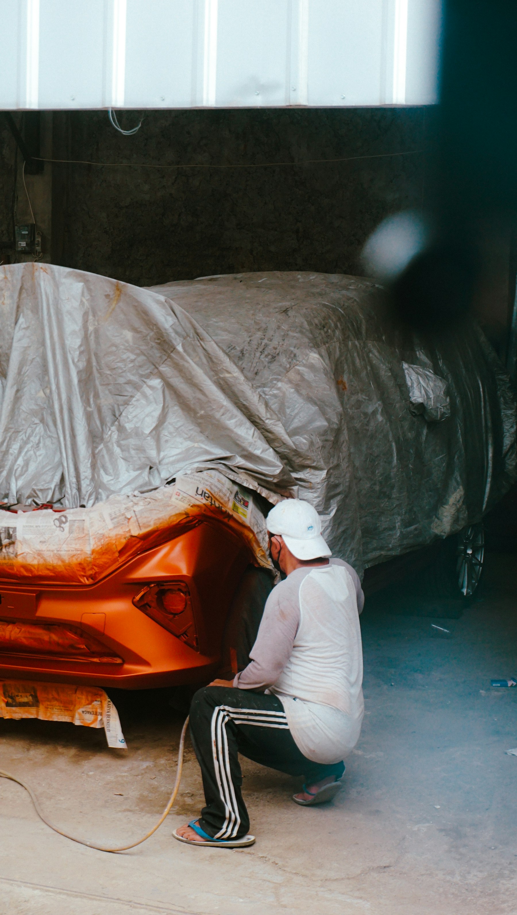 Painter spraying a car in a booth